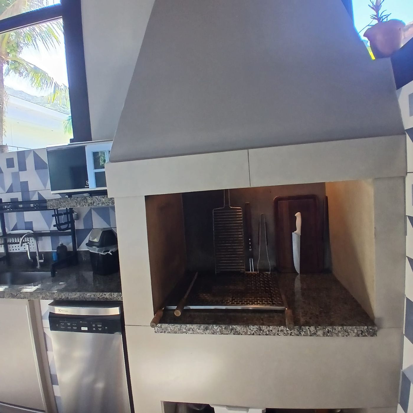 Churrasqueira com utensílios e lava-louças ao lado