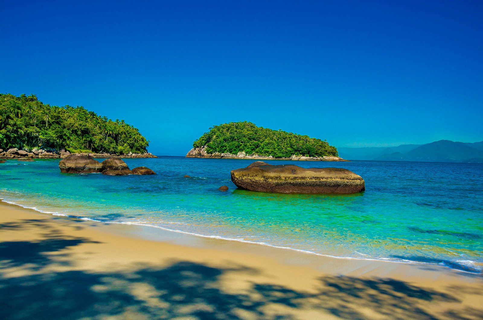 Praia de areia dourada e águas azul-turquesa com a Ilha das Couves ao fundo